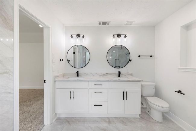Primary bath features bright and light Quartz countertops, white cabinets, and stunning tile flooring. | Image 16