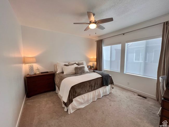 Bedroom with ceiling fan, light carpet, and a textured ceiling | Image 6