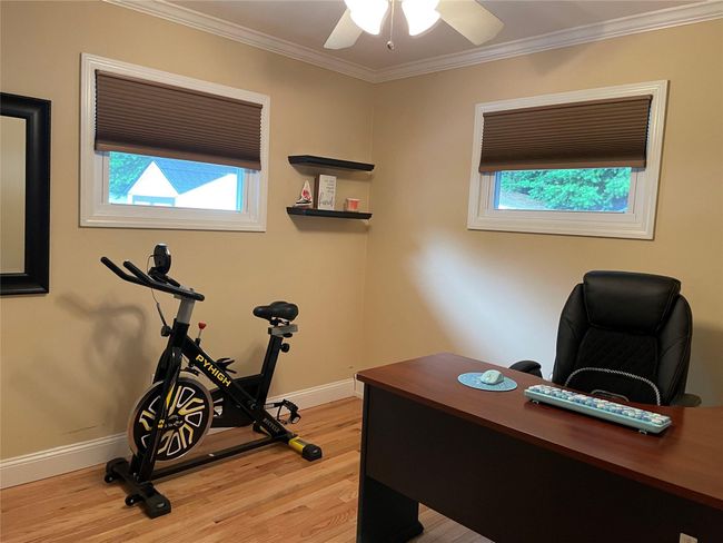 Office area featuring light wood-type flooring, healthy amount of natural light, baseboards, ornamental molding, and a ceiling fan | Image 26