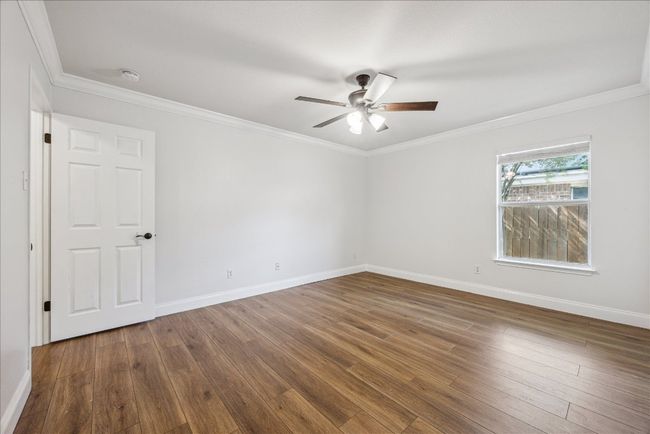 Oversized secondary bedroom with large windows, crown molding, ceiling fan, and closet with sliding doors | Image 23