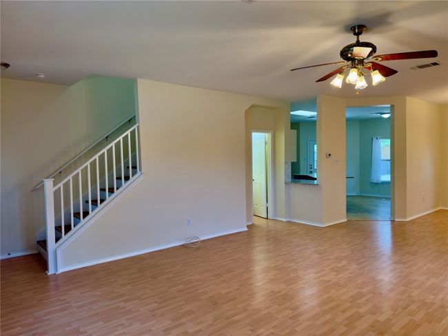 Unfurnished living room featuring light wood-style flooring, a ceiling fan, and stairs | Image 17