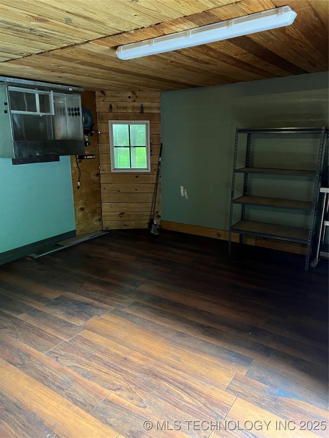 Basement featuring dark wood finished floors, baseboards, and wood walls | Image 29