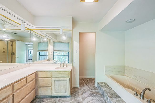 Bathroom with a garden tub, vanity, and marble finish floor | Image 25