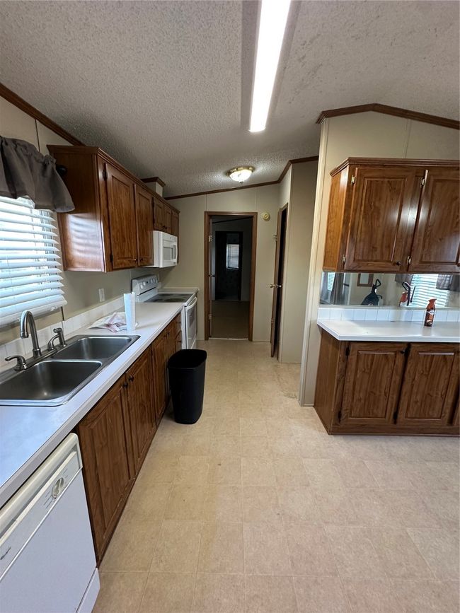 Kitchen featuring range, dishwashing machine, a sink, crown molding, and light countertops | Image 14