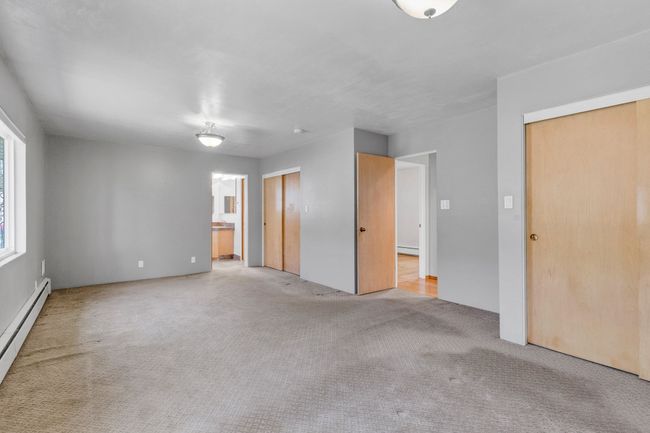 Carpeted spare room with baseboard heating and visible vents | Image 12