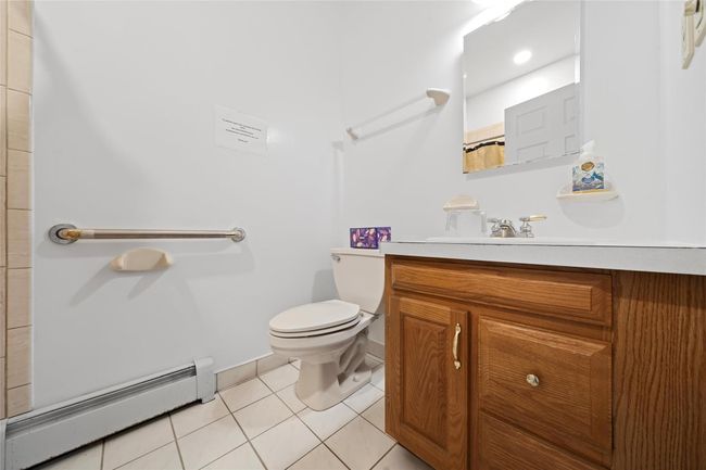 Bathroom featuring baseboard heating, tile patterned floors, vanity, curtained shower, and toilet | Image 40
