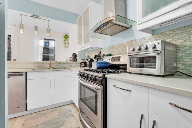 Kitchen with appliances with stainless steel finishes, island exhaust hood, a sink, light countertops, and tasteful backsplash | Image 4