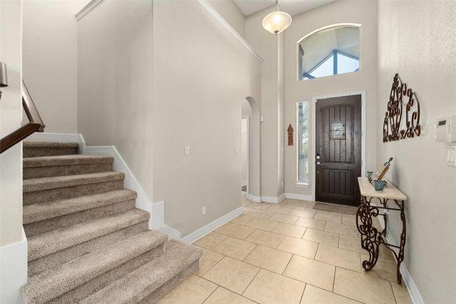 Foyer with stairway, baseboards, light tile patterned flooring, arched walkways, and a towering ceiling | Image 19