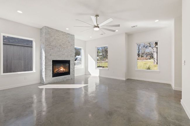 Unfurnished living room featuring recessed lighting, concrete floors, a stone fireplace, and baseboards | Image 8