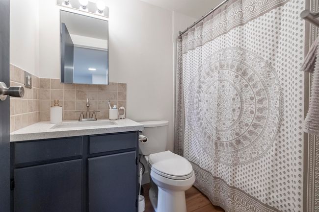 Full bathroom with vanity, a shower with curtain, toilet, decorative backsplash, and wood finished floors | Image 20