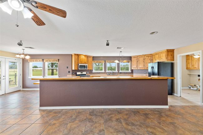 Kitchen with appliances with stainless steel finishes, hanging light fixtures, a chandelier, a textured ceiling, and butcher block counters | Image 8
