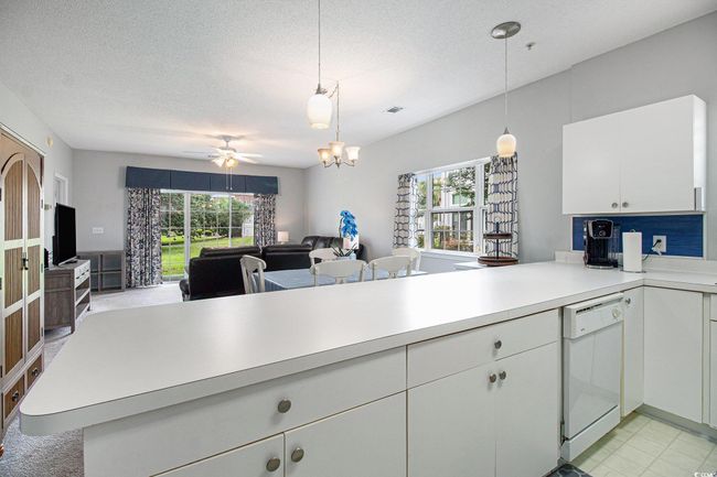 Kitchen with white dishwasher, open floor plan, light countertops, healthy amount of natural light, and a textured ceiling | Image 4