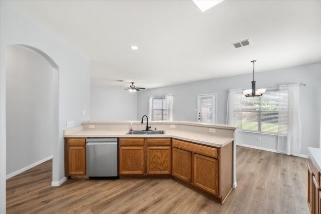 Kitchen featuring dishwasher, brown cabinetry, new laminate flooring, plenty of natural light, and recessed lighting | Image 11