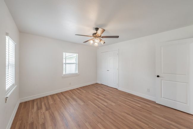 Unfurnished bedroom with light wood-type flooring, baseboards, a closet, and a ceiling fan | Image 10