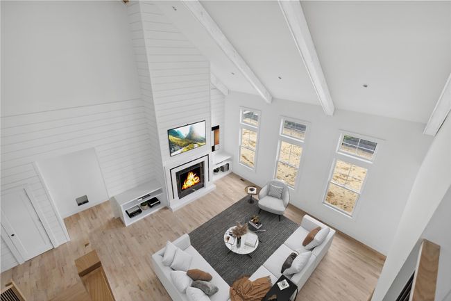 Living area with lofted ceiling with beams, a lit fireplace, and wood finished floors | Image 14