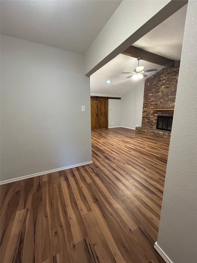 Unfurnished living room with ceiling fan, wood finished floors, and a fireplace | Image 7