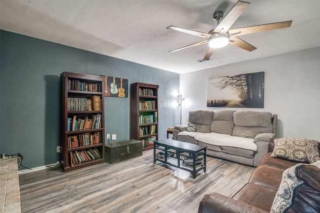 Living area with wood finished floors, ceiling fan, a textured wall, and a textured ceiling | Image 16