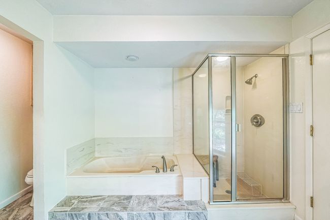 Full bathroom featuring toilet, a garden tub, and a shower stall | Image 26