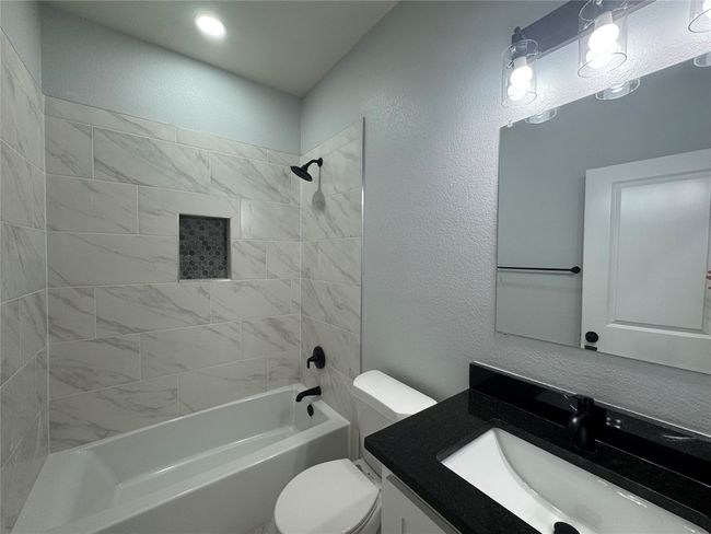 Full bathroom featuring vanity, a textured wall, and shower / bathtub combination | Image 22
