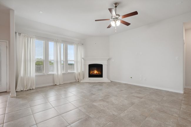 Unfurnished living room with a glass covered fireplace, a ceiling fan, and light tile patterned floors | Image 14