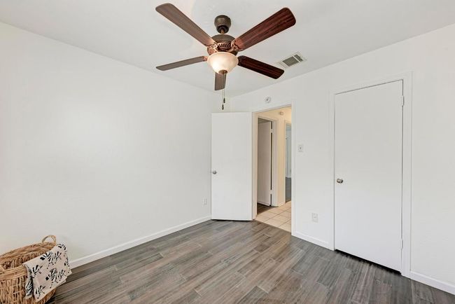 Unfurnished bedroom featuring ceiling fan, visible vents, baseboards, and wood finished floors | Image 22
