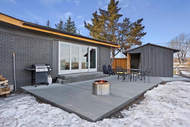 Snow covered back of property featuring a fire pit, a patio area, entry steps, and an outdoor structure | Image 47
