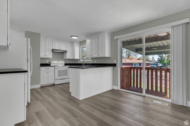 Kitchen featuring white cabinetry, white appliances, and a peninsula | Image 11