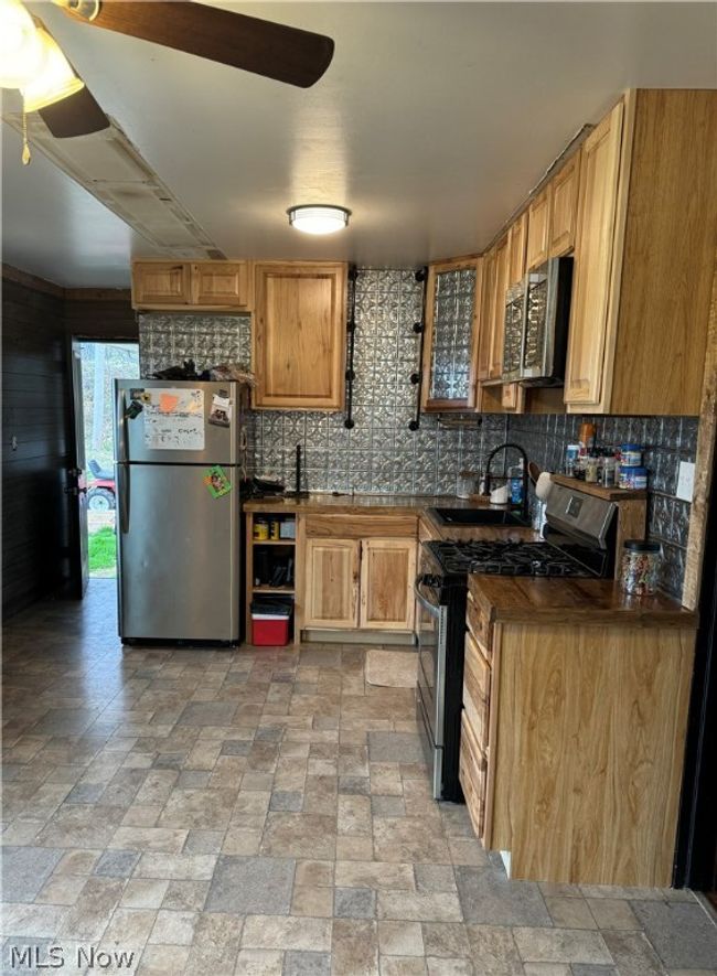 Kitchen featuring tasteful backsplash, stainless steel appliances, light tile flooring, and ceiling fan | Image 4