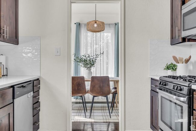 Kitchen featuring stainless steel appliances, decorative backsplash, light countertops, and dark brown cabinets | Image 12