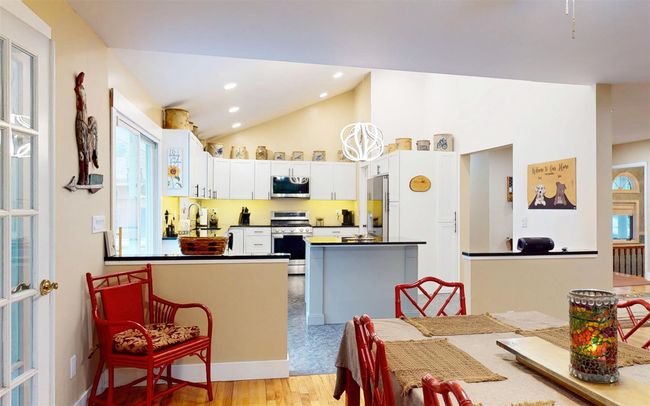 Kitchen featuring stainless steel appliances, dark countertops, vaulted ceiling, white cabinetry, and light wood-type flooring | Image 14