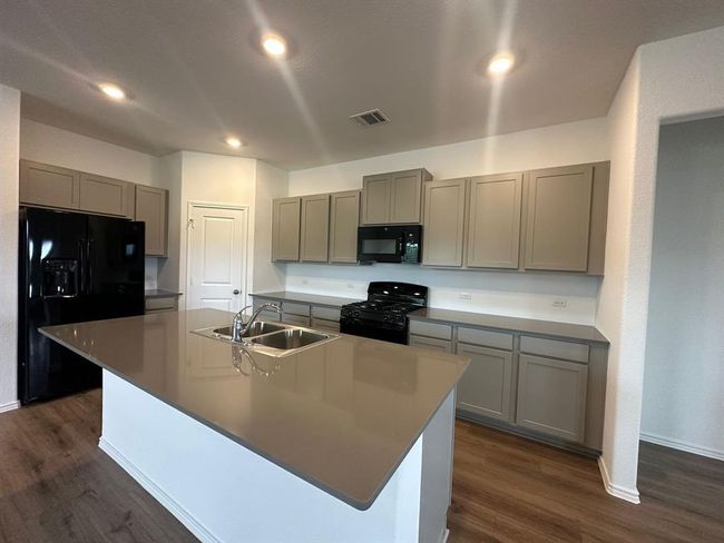 Kitchen with black appliances, gray cabinets, a sink, dark wood-type flooring, and recessed lighting | Image 16