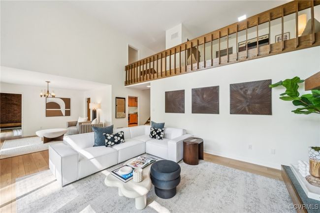 Living area featuring a high ceiling, a chandelier, wood finished floors, and baseboards | Image 16