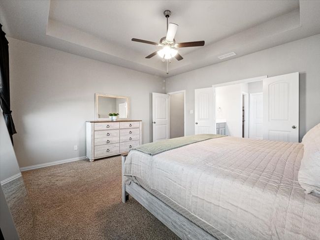 Carpeted bedroom featuring baseboards, visible vents, a tray ceiling, and a ceiling fan | Image 13