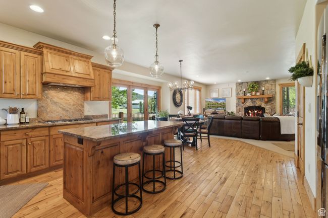 Kitchen with a center island, gas cooktop, light wood finished floors, backsplash, and recessed lighting | Image 4