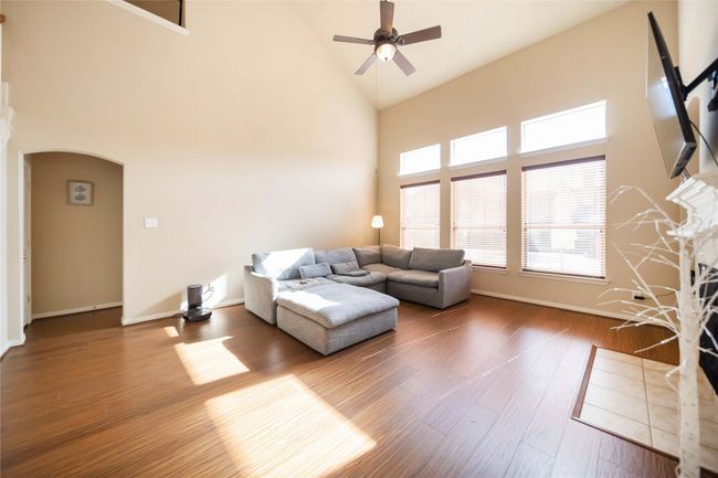 Living room with high vaulted ceiling, arched walkways, a ceiling fan, and wood finished floors | Image 15