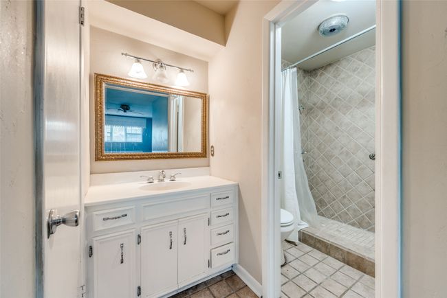 Bathroom with toilet, vanity, tile patterned flooring, and a tile shower | Image 19