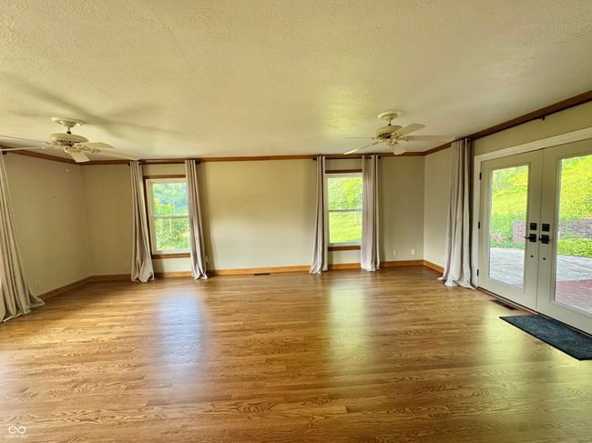 empty room featuring ceiling fan, french doors, a textured ceiling, wood finished floors, and healthy amount of natural light | Image 46
