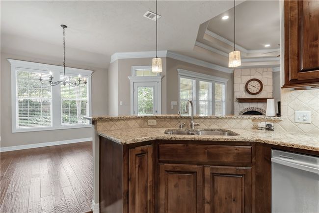 Kitchen with dishwasher, a sink, hardwood / wood-style flooring, decorative backsplash, and light stone counters | Image 18