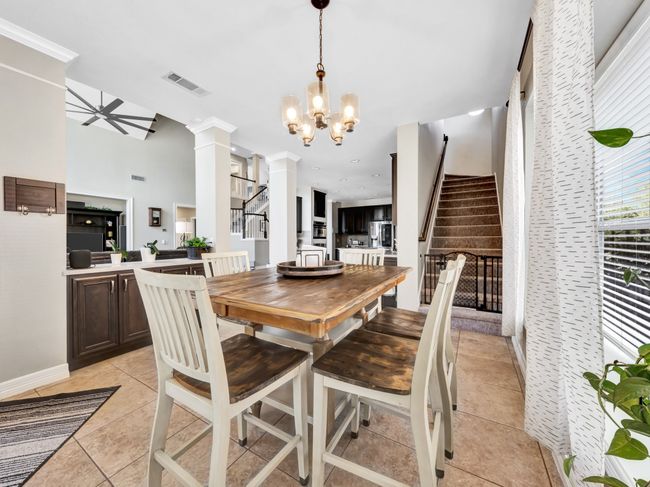 Breakfast room featuring light tile floors, chandelier, visible vents, stairway, and ornate columns | Image 12