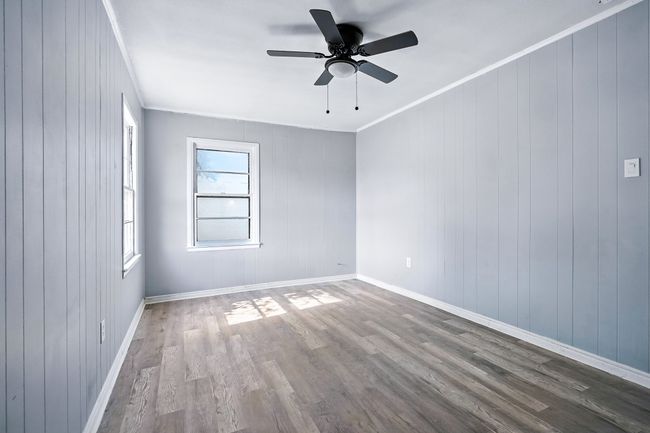 Spare room featuring wood finished floors, a ceiling fan, crown molding, and wood walls | Image 17