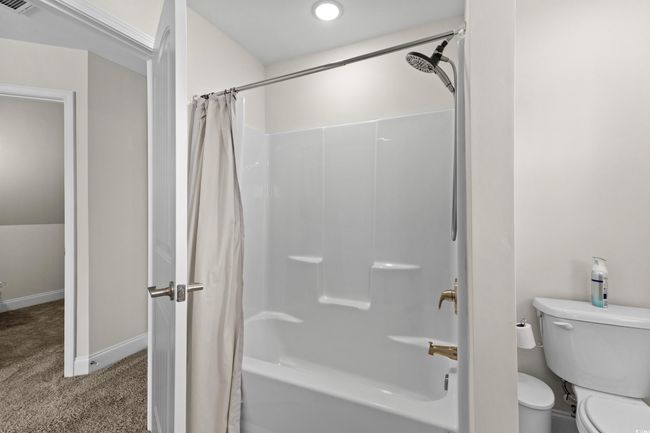 Bathroom featuring shower / tub combo with curtain, toilet, and baseboards | Image 18