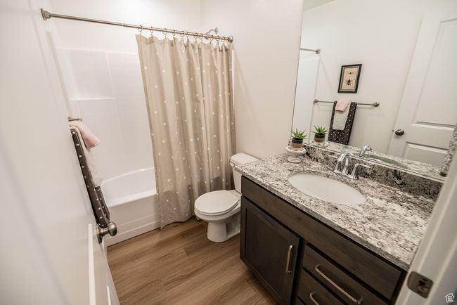 Full bath featuring wood finished floors, vanity, and shower / bathtub combination with curtain | Image 12