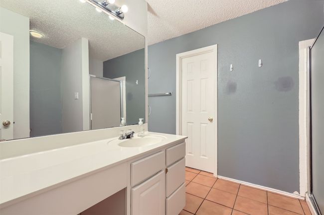 Bathroom featuring a shower stall, a textured ceiling, tile patterned floors, and vanity | Image 17