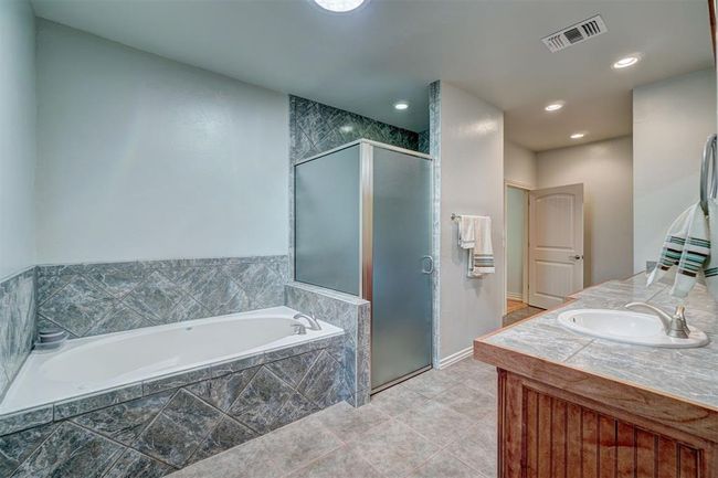 Bathroom featuring tile patterned floors, a stall shower, a bath, vanity, and visible vents | Image 26