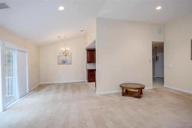Spare room with a chandelier, light colored carpet, vaulted ceiling, and recessed lighting | Image 7