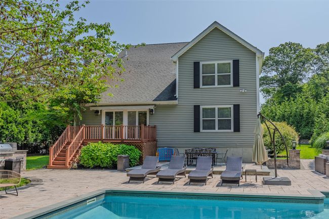 Rear view of property with a wooden deck, stairway, an outdoor pool, and a patio area | Image 35