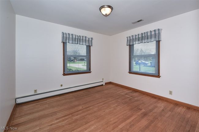 Empty room featuring a baseboard heating unit, plenty of natural light, wood finished floors, and visible vents | Image 35