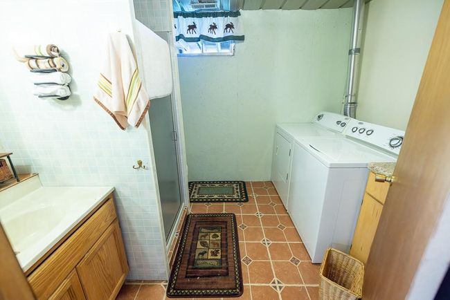 Washroom featuring tile walls, light tile patterned floors, washer and clothes dryer, and sink | Image 20