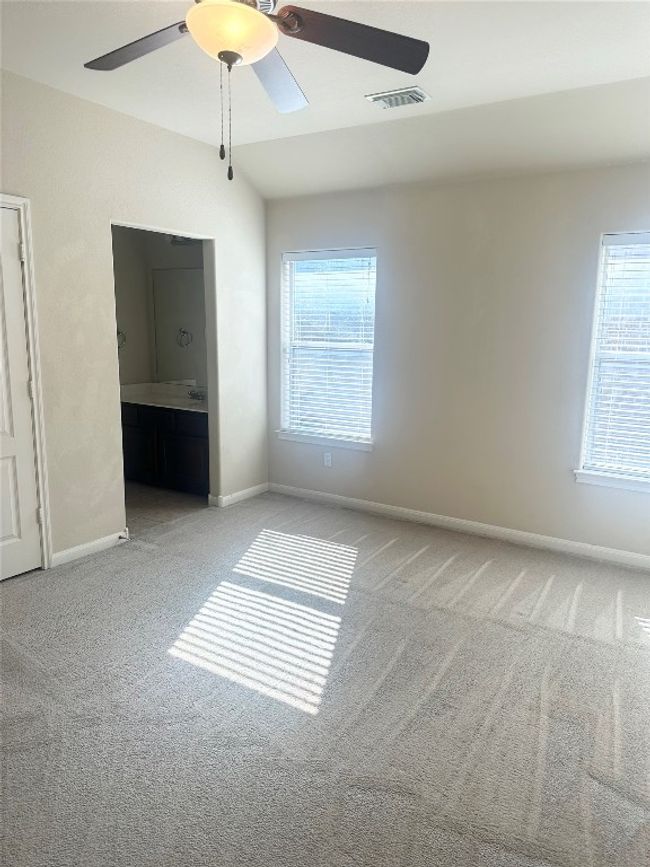 Unfurnished bedroom featuring carpet flooring, ensuite bathroom, ceiling fan, and lofted ceiling | Image 12