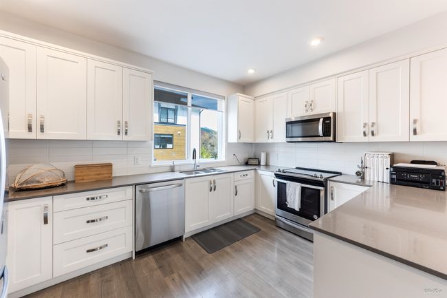 Kitchen with white cabinetry, a sink, stainless steel appliances, recessed lighting, and wood finished floors | Image 6